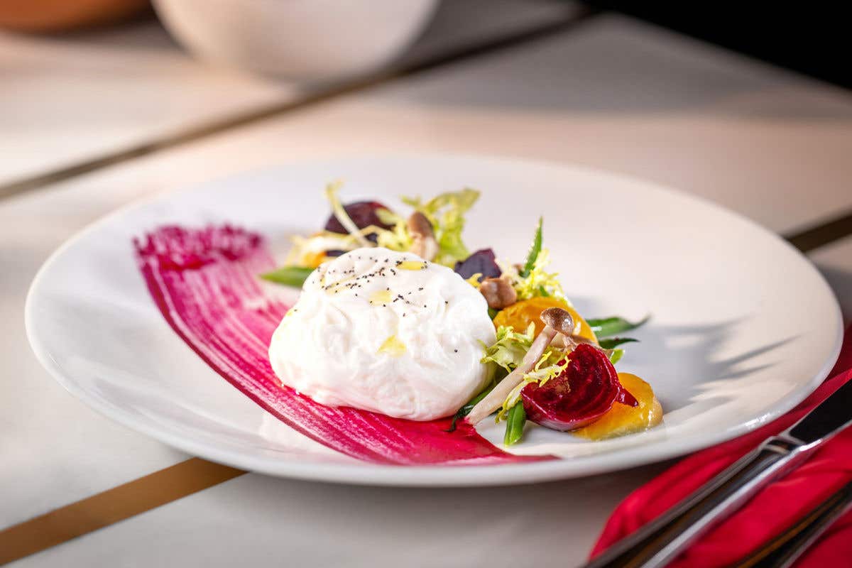 Burrata served with colorful beets and greens on a beet purée smear.