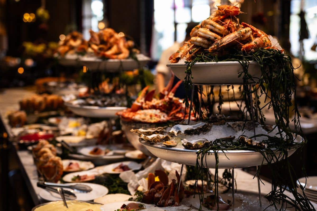Seafood buffet display with tiered trays of oysters, crab, and shrimp on ice.