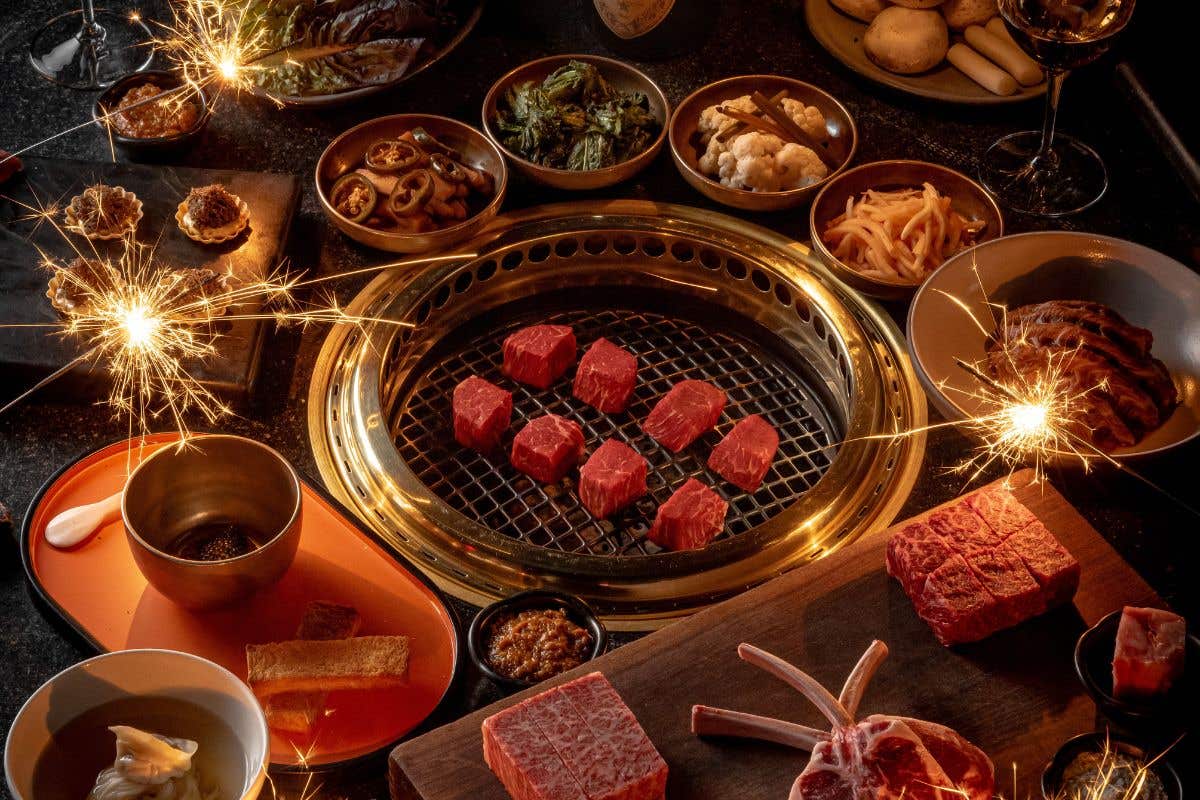 Steak grilling on a Hibachi surrounded by side dishes and sparklers. 