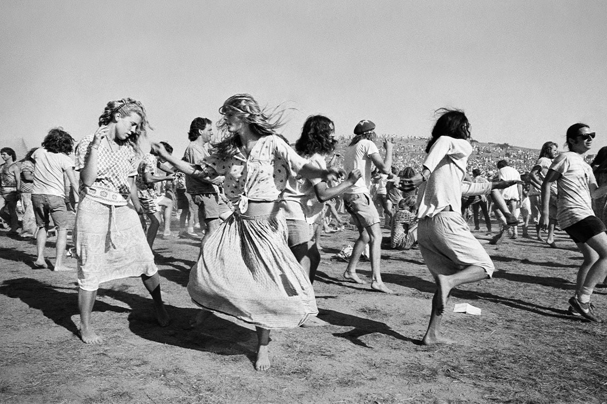 A black and white photo of a group of people dancing outdoors in a large open field
