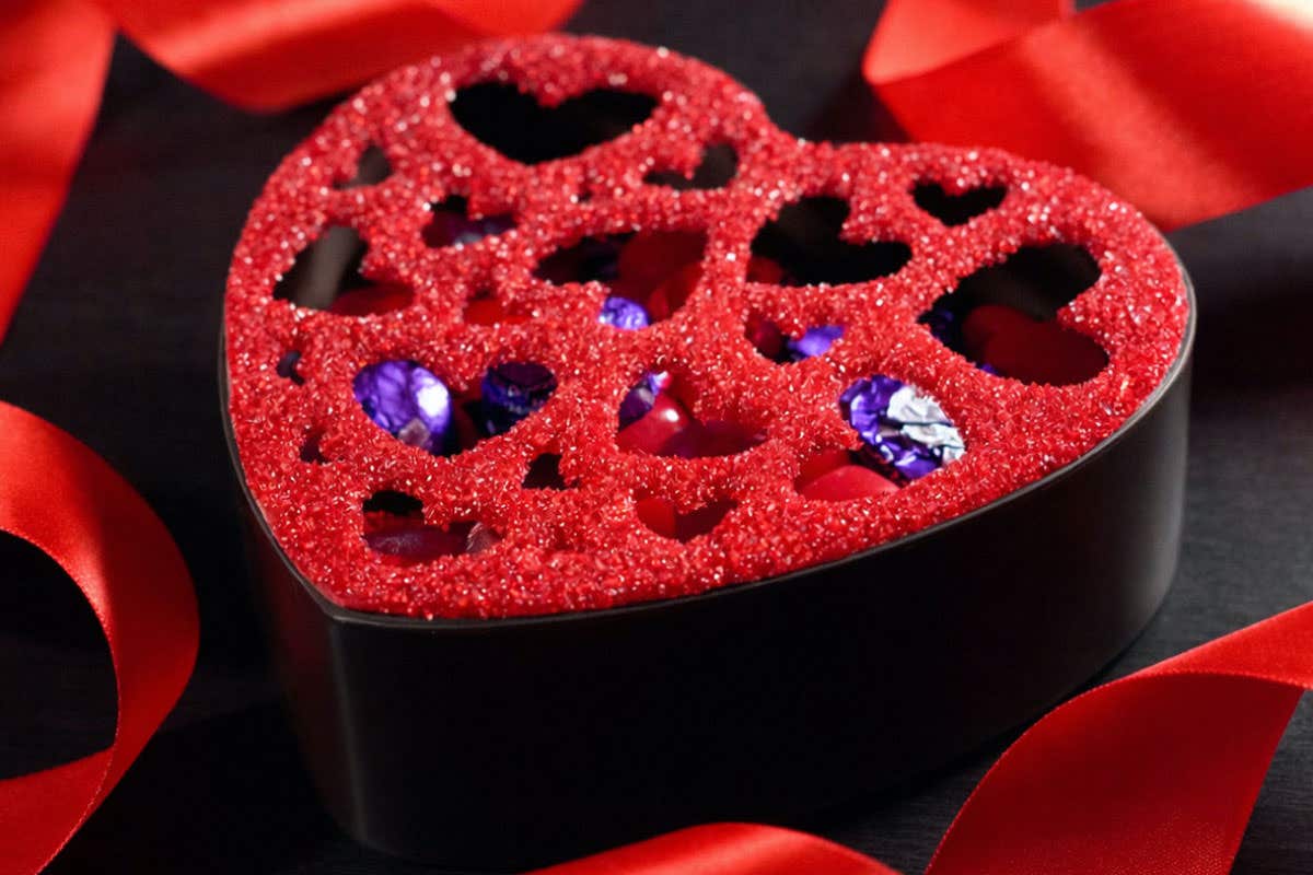 TAO Chocolate box surrounded by red ribbon and purple wrapped chocolate inside.