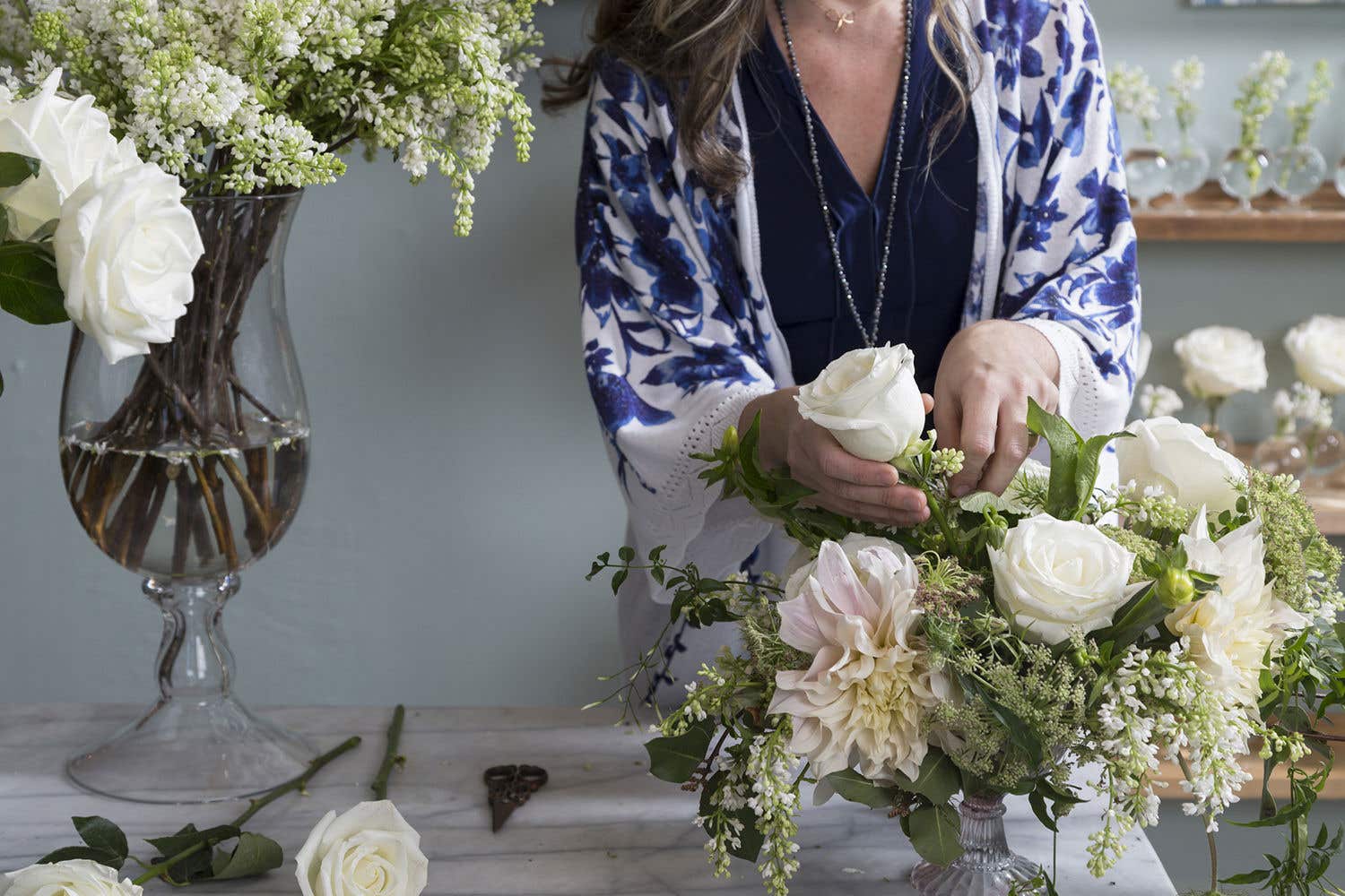 A few bouquets of flowers and a person arranging them.