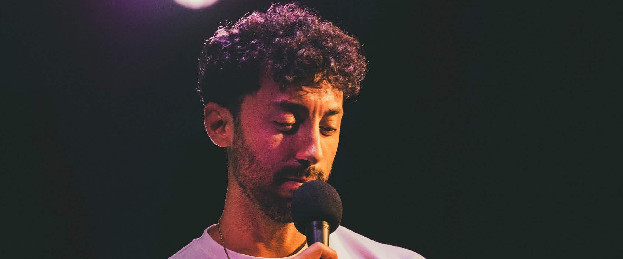 Morgan Jay in a white shirt holding a microphone.