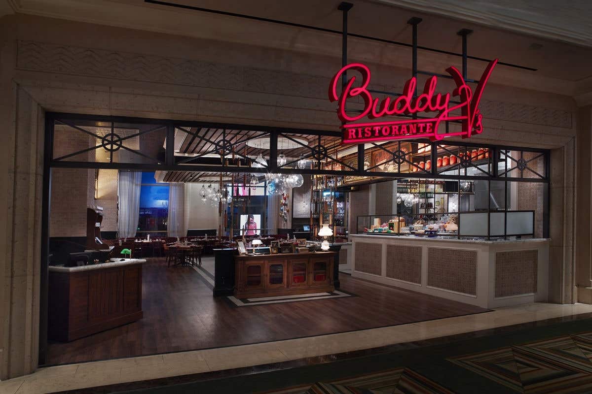Buddy V’s Ristorante entrance with illuminated signage and a view into the dining room.