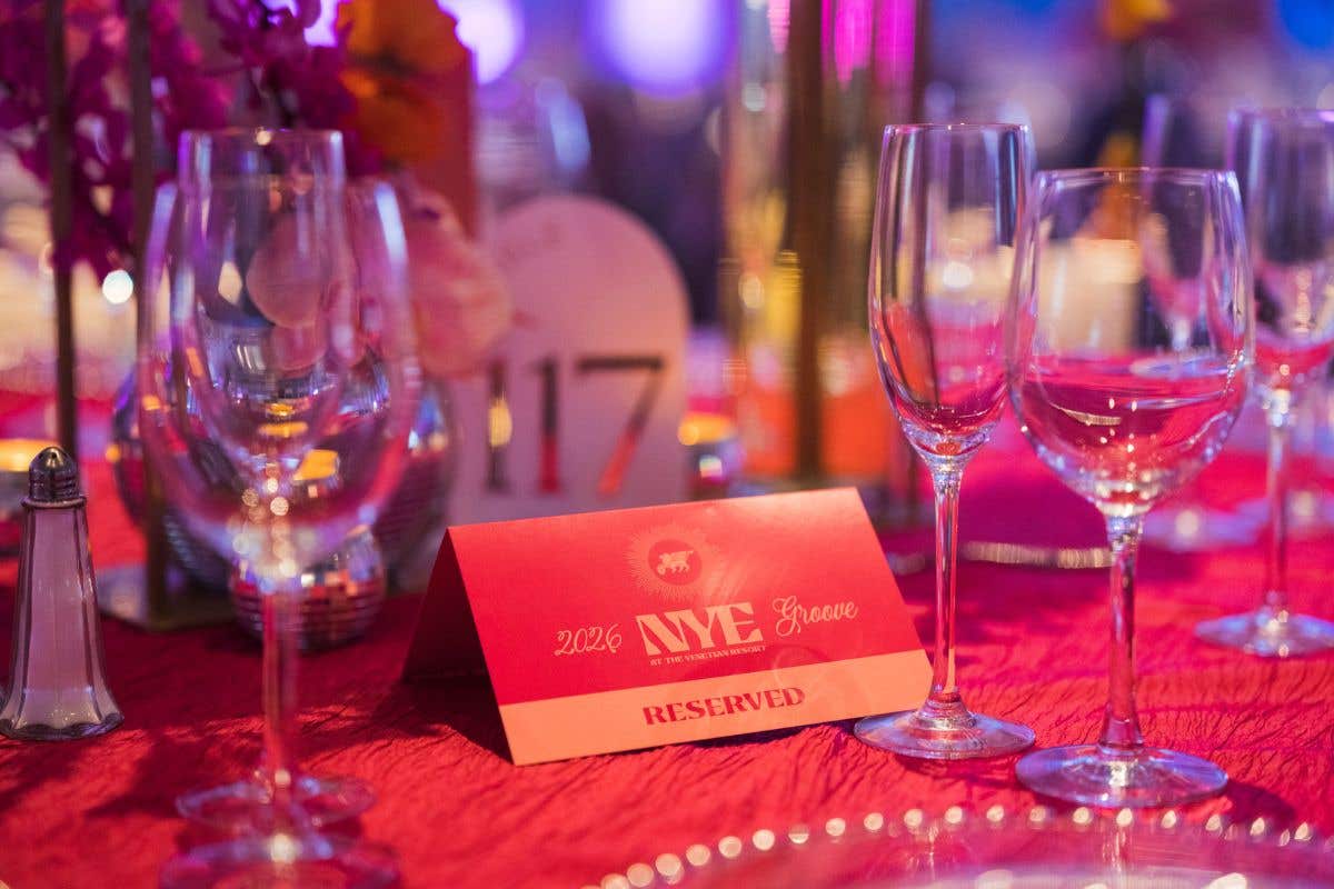 Reserved event table setting with wine glasses and Venetian branding.