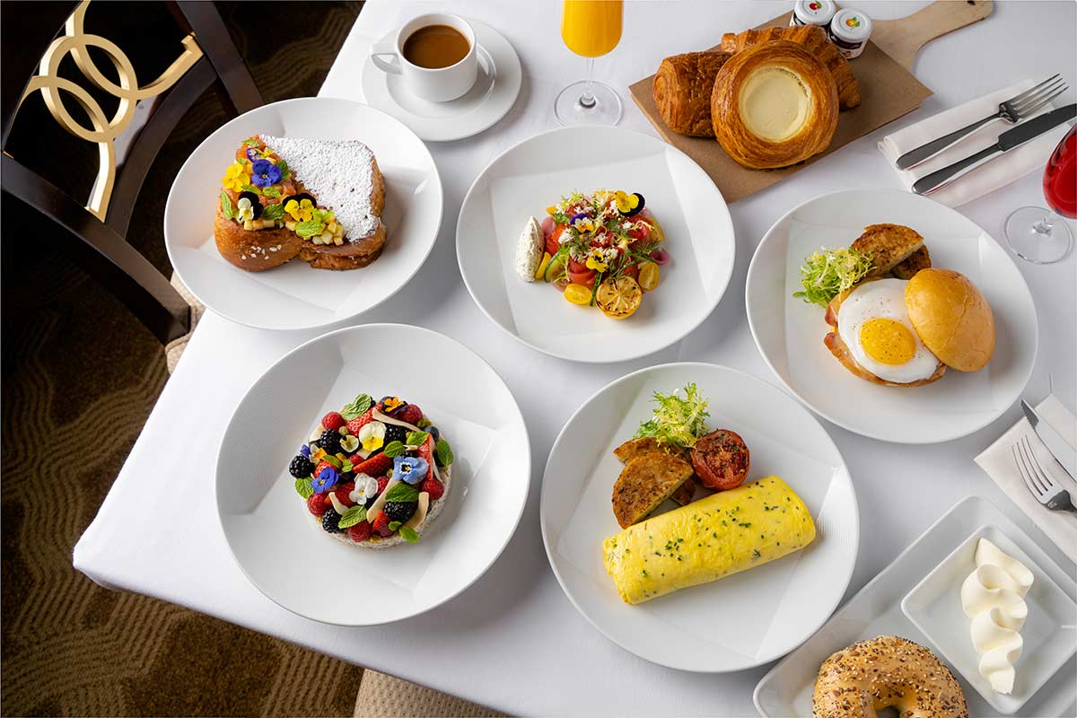 A table set with various breakfast dishes, including eggs, pastries, and fruit.