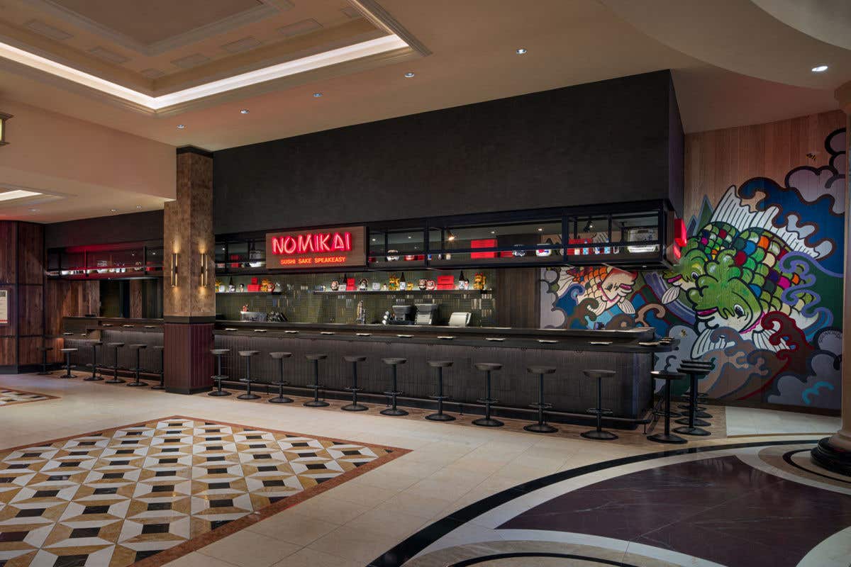 Modern bar interior with long counter and stools, featuring a neon sign reading “NOMIKAI Sushi Sake Speakeasy.”
