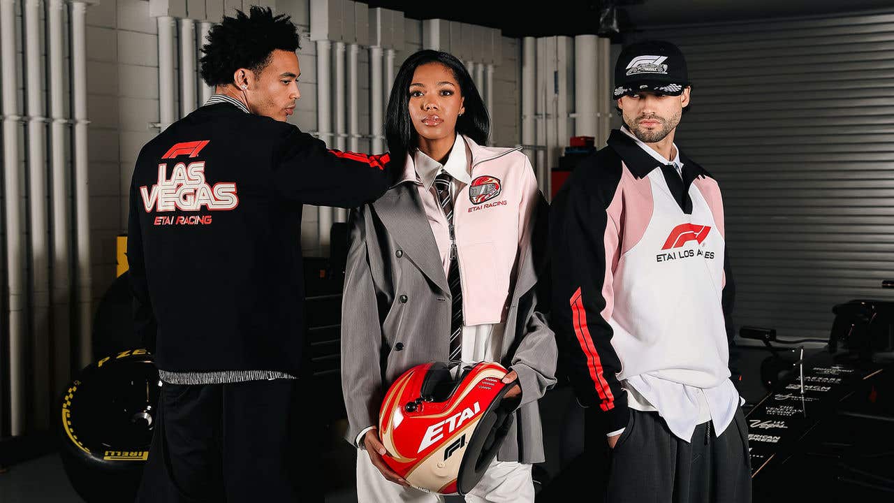 Three people in Etai F1 clothing, one holding a helmet.