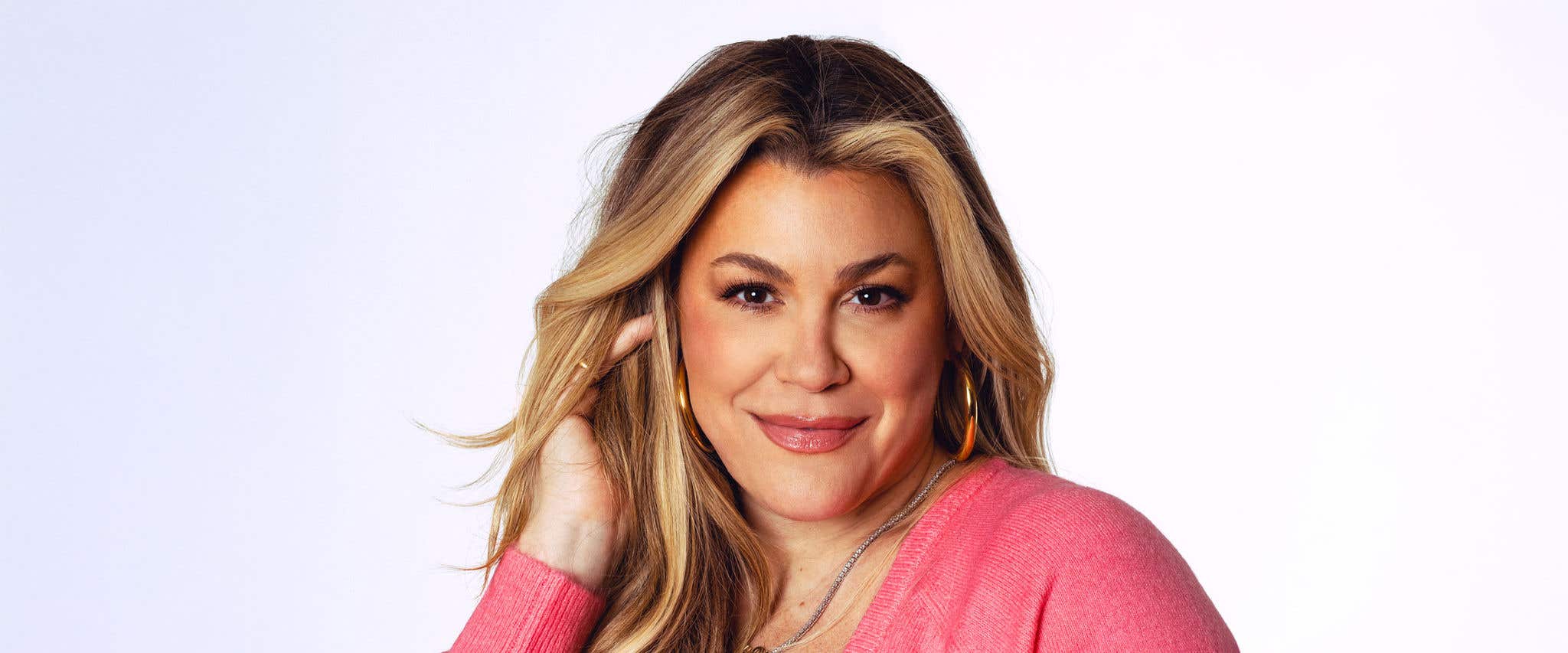 Heather McMahan in a pink top looking at the camera in front of a white background.