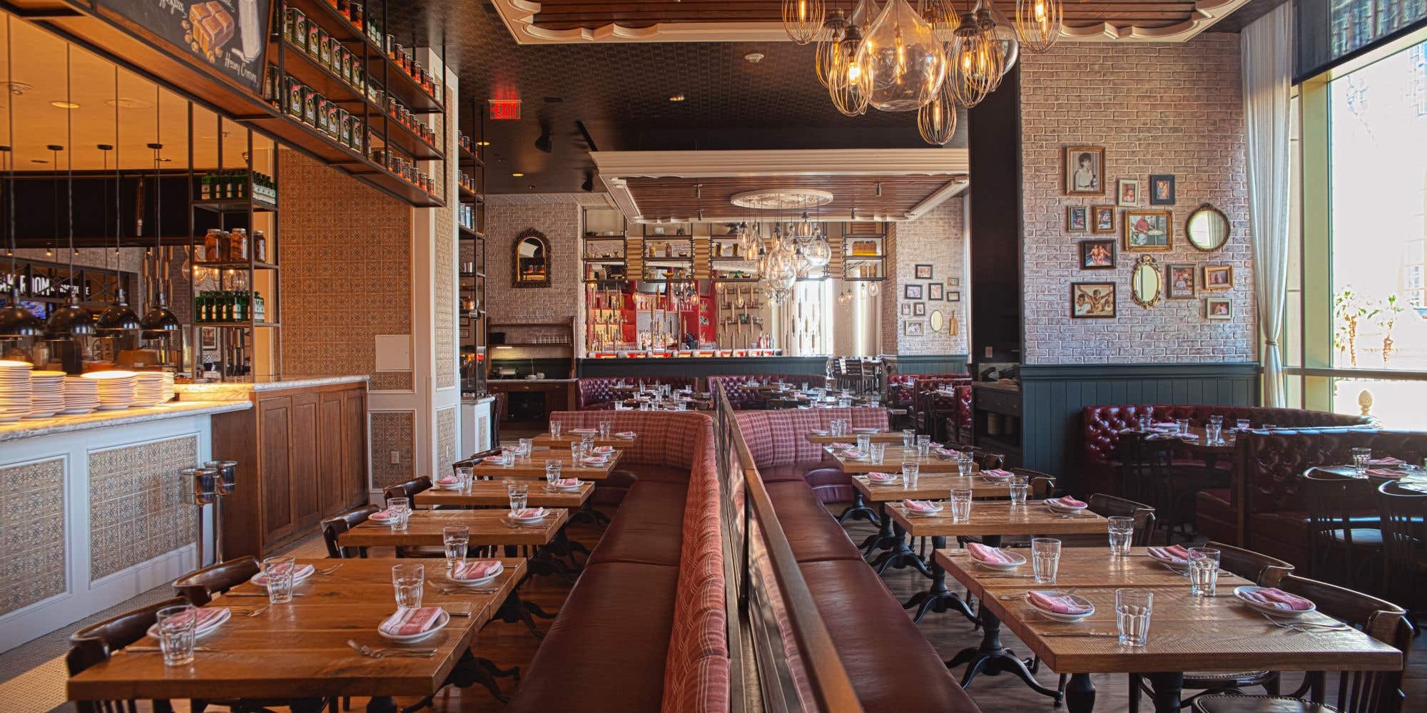Warm, inviting restaurant interior with booth seating, wood tables, and pendant lighting.