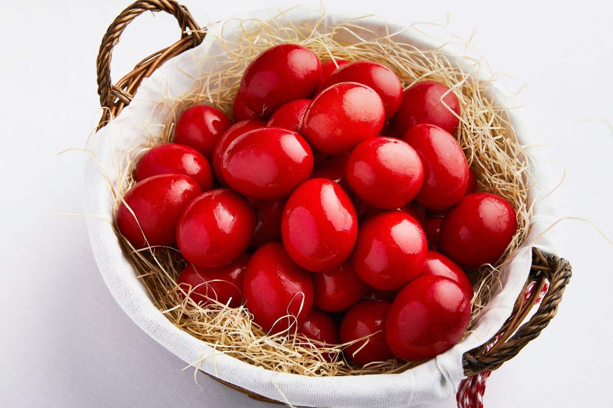 Bright red eggs displayed in a straw filled basket.