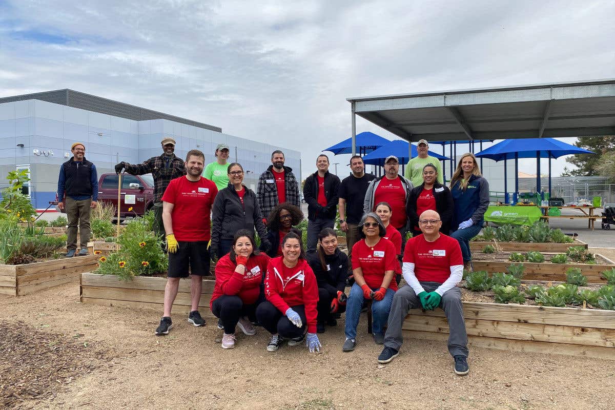 A group of volunteers and farmers pose in garden, ready for planting.