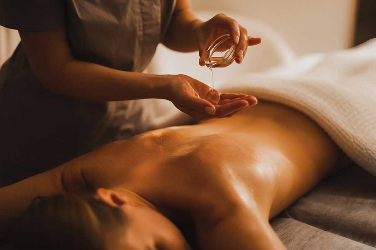 A woman lying face down receives a massage with essential oils.