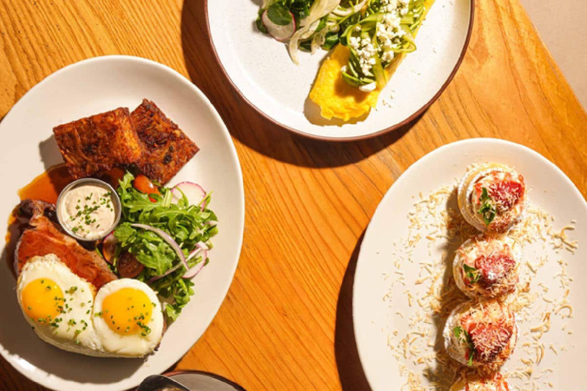 Three plated brunch dishes on a wooden table.