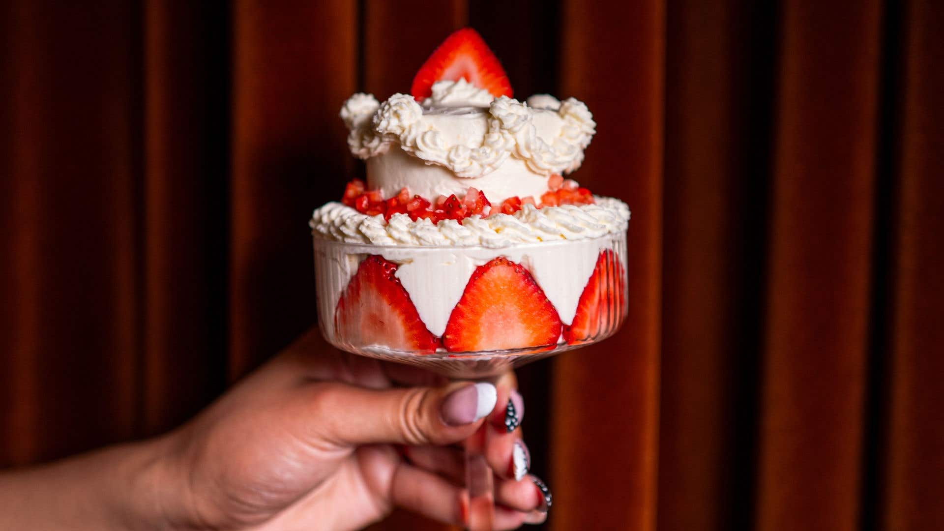 Strawberry and cream dessert layered in a stemmed glass and topped with fresh strawberries.