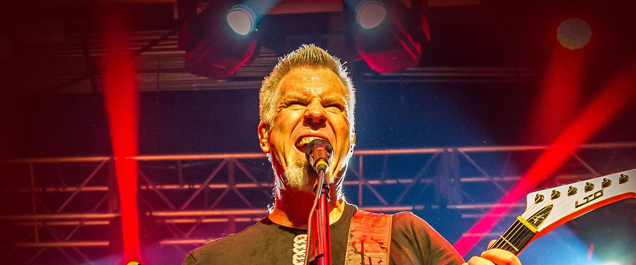 Lead singer of Damaged Inc screaming into a microphone on stage.