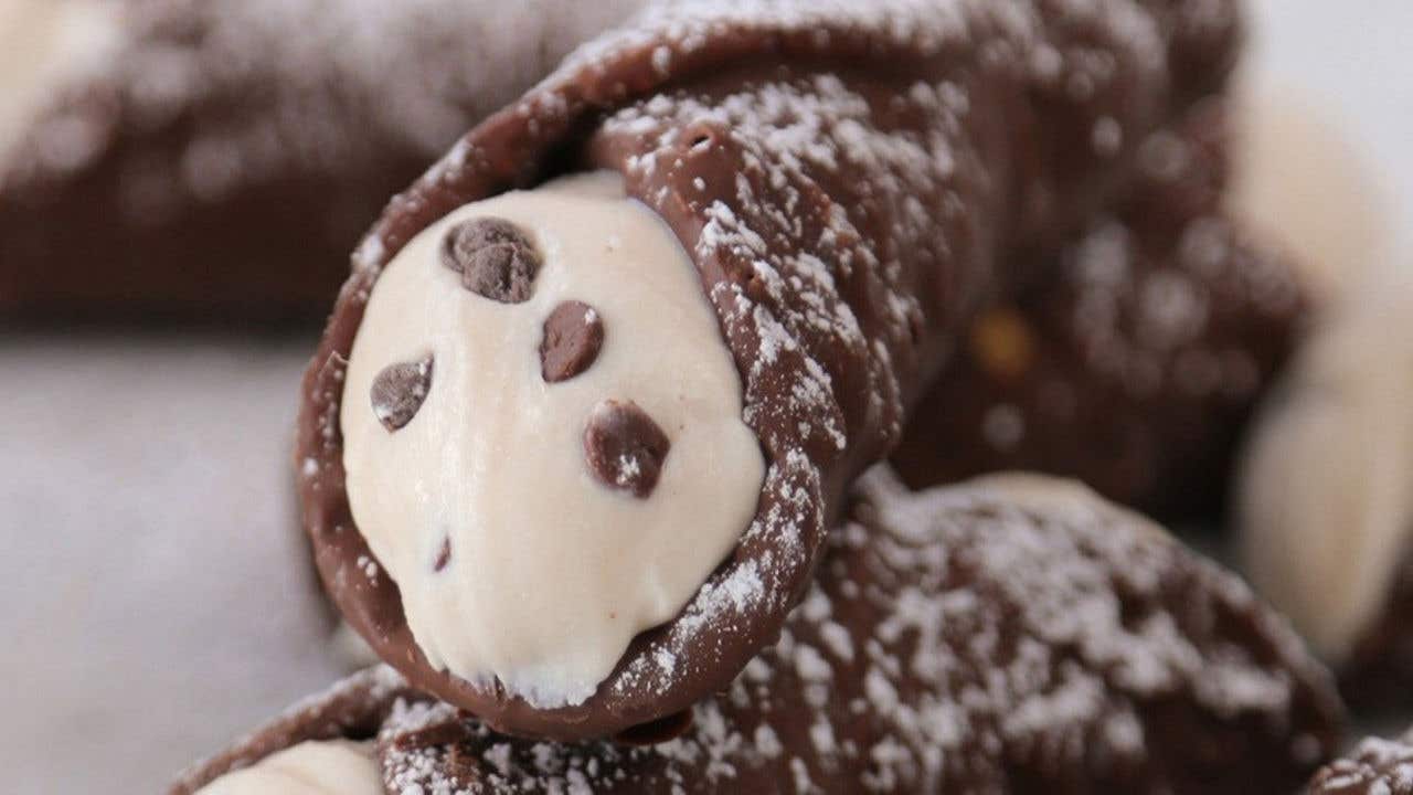 Plate of traditional chocolate Italian cannoli topped with powdered sugar.