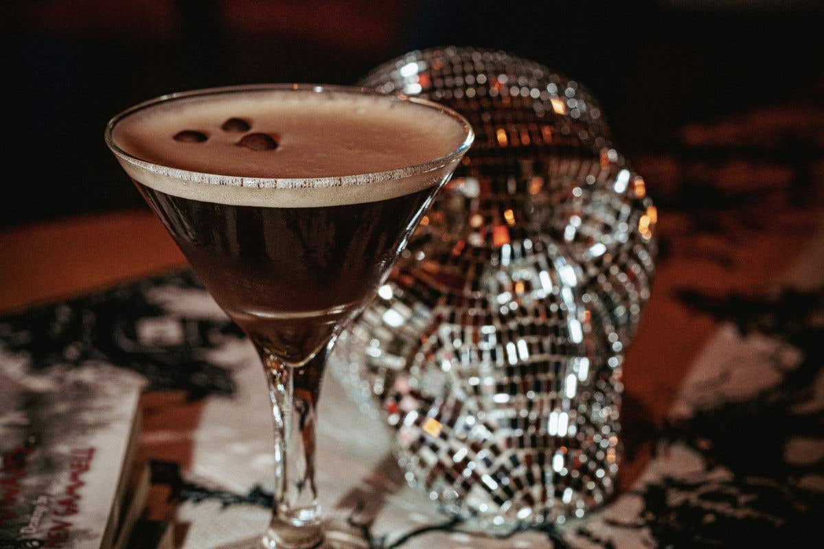 Coffee cocktail in a martini glass with a mirrored skull decoration in the background.