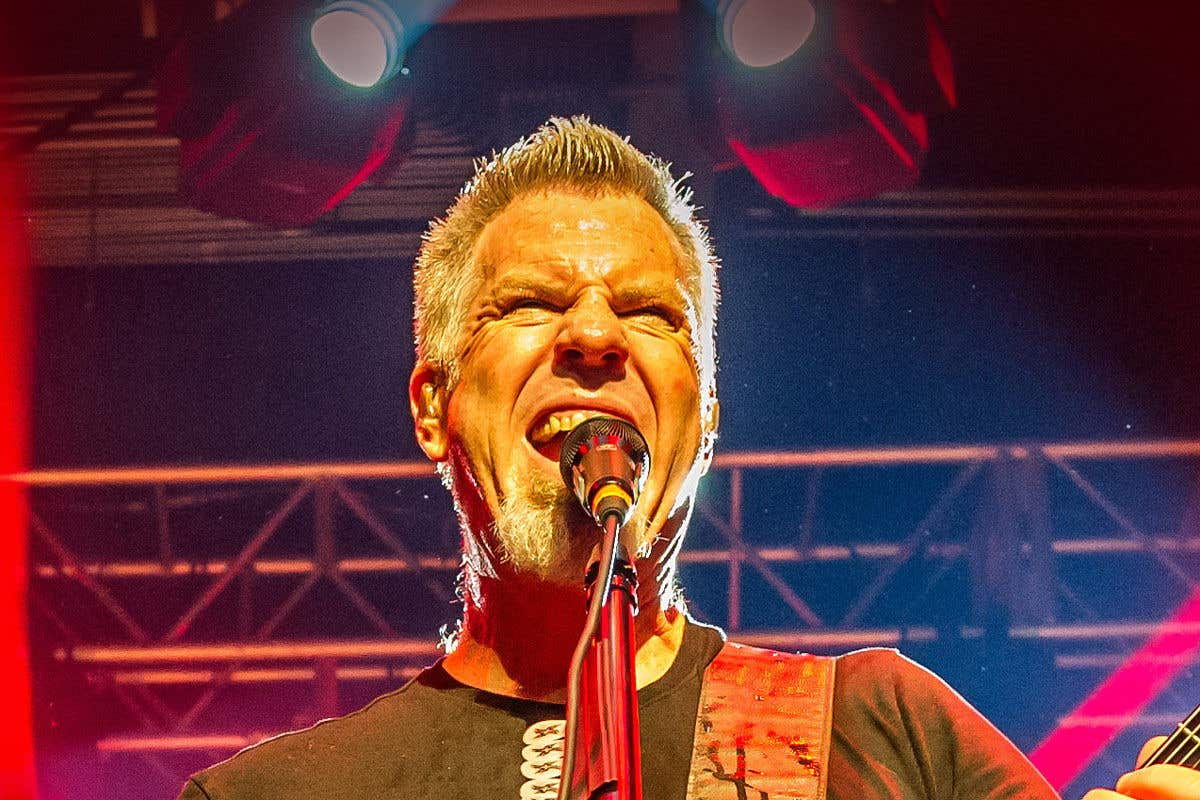 Lead singer of Damaged Inc screaming into a microphone on stage.