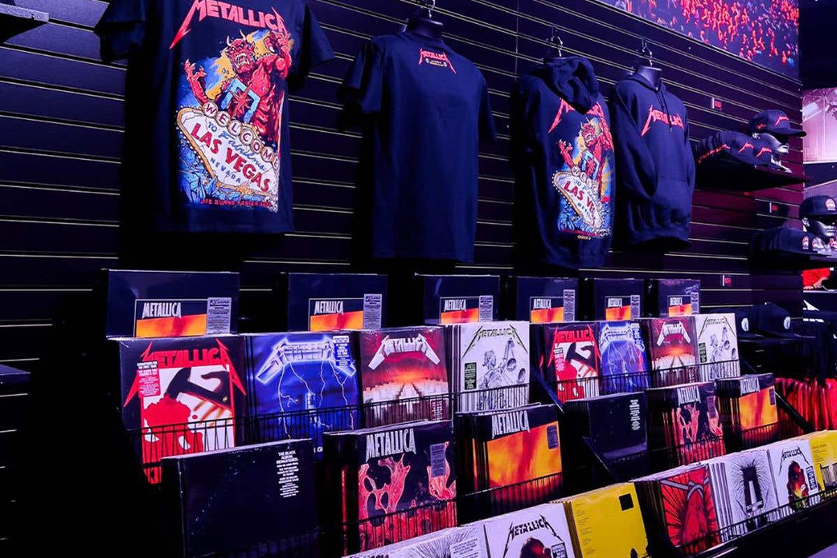 A wall of Metallica merchandise, showing t-shirts, albums and hats.
