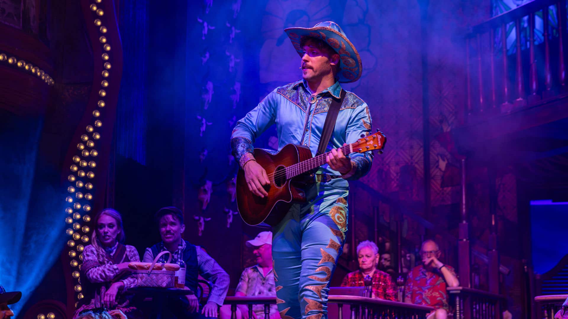 Talent in a blue cowboy costume playing a guitar. 