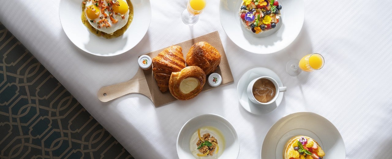 A table set with various breakfast items including pastries, fruit, and coffee.