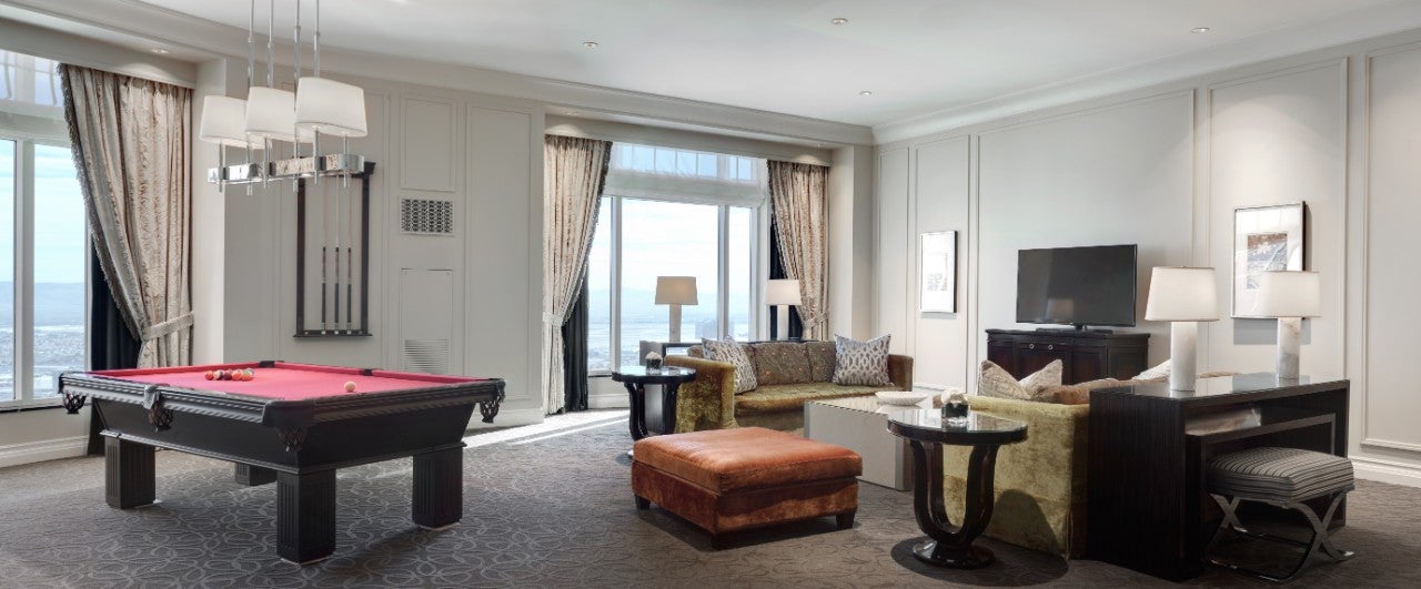 Luxurious living room with a pool table, TV, sofas, and large windows overlooking a scenic view.