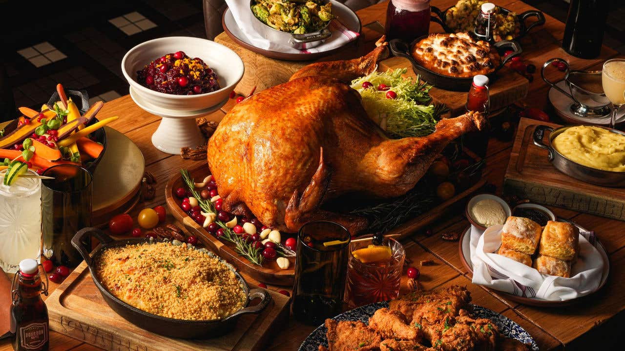 Table spread of Thanksgiving dishes including a roasted turkey, fried chicken, carrots and marshmallow yams. 