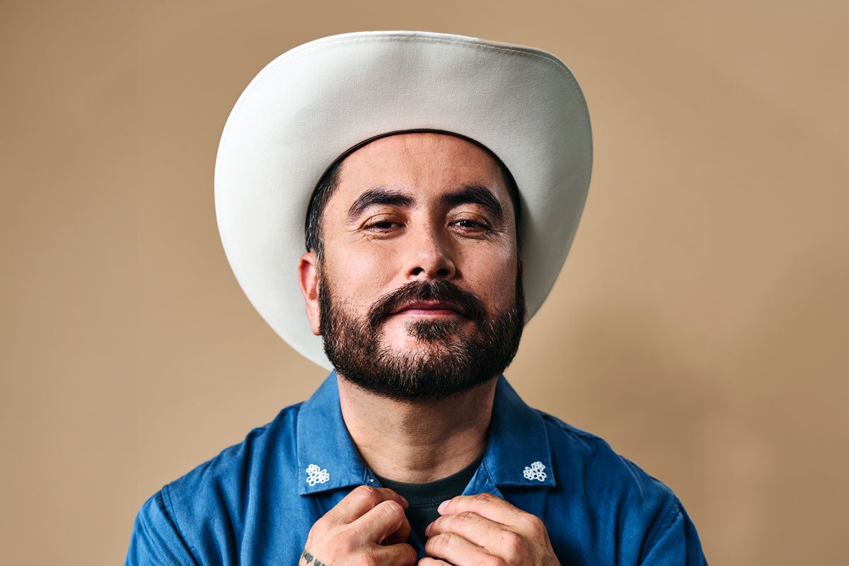 Alfred Robles wearing a cowboy hat and a blue shirt with white collar designs.