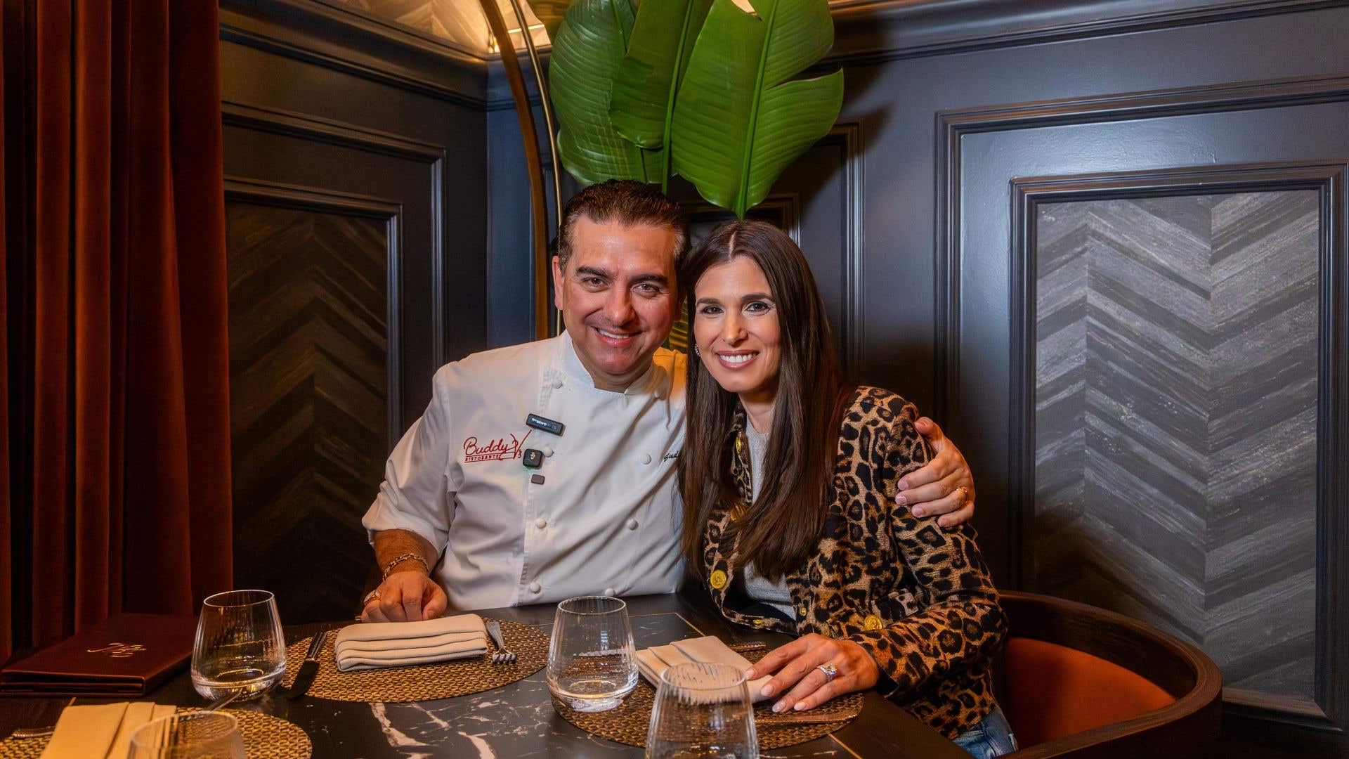 Two people posing together at an upscale restaurant table.