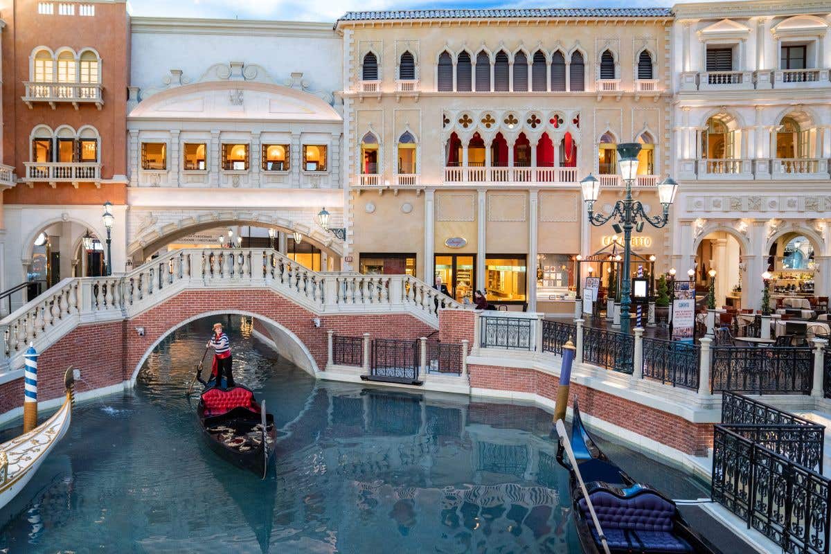 Gondolier rowing a gondola through the canal by St. Marks Square inside The Venetian Resort. 