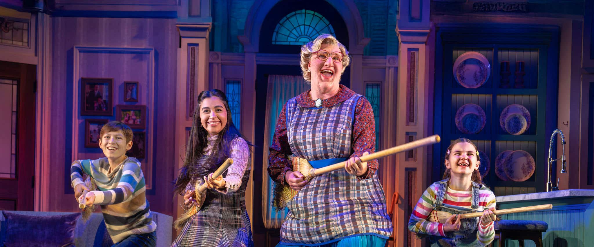 Mrs. Doubtfire holding a broom with the kids on each side of her. 