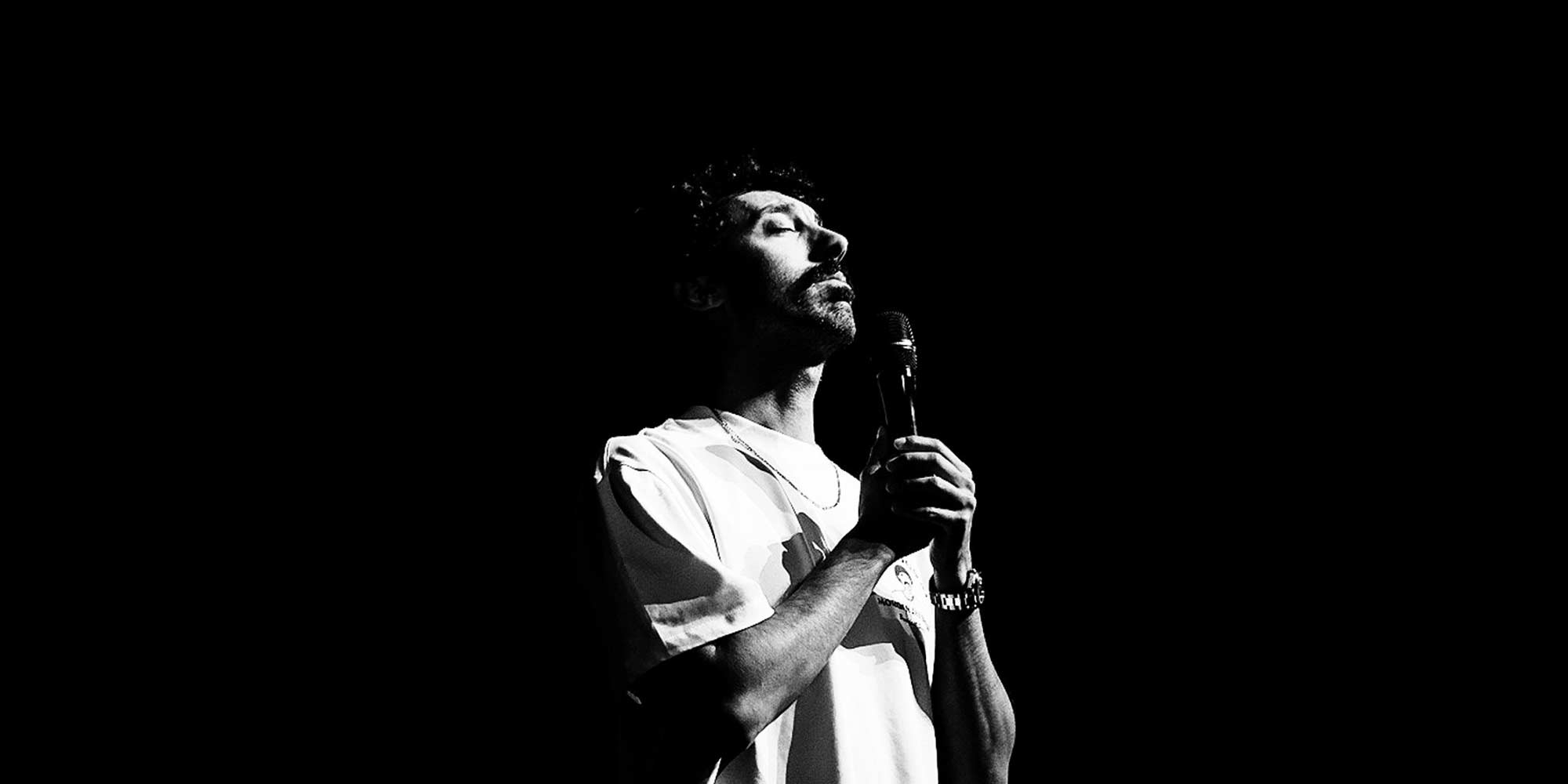 High contrast black and white photo of Morgan Jay standing with a microphone
