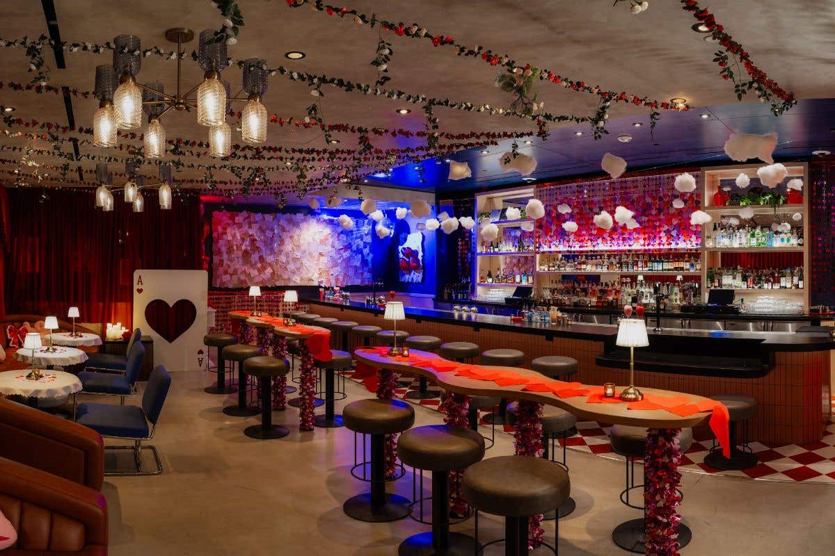Valentine’s‑themed speakeasy bar decorated with red and pink garlands, heart accents, and festive lighting.