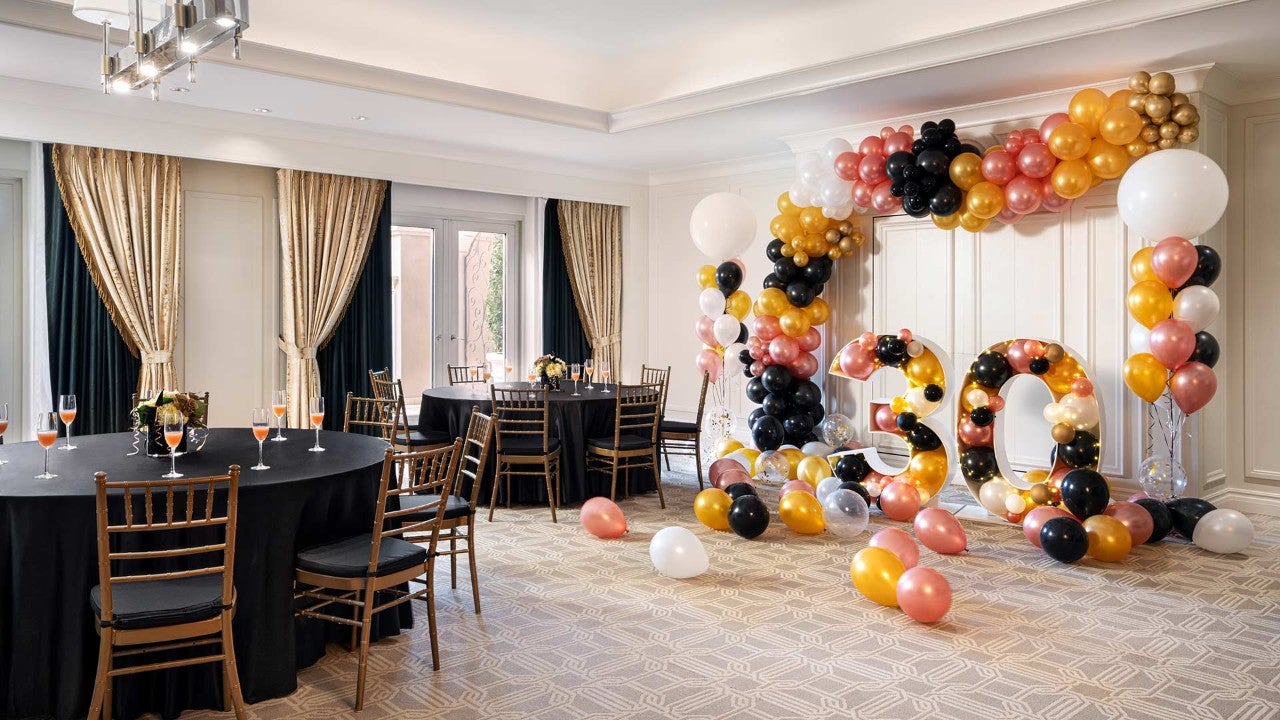 A decorated meeting room with tables, chairs, and balloons.