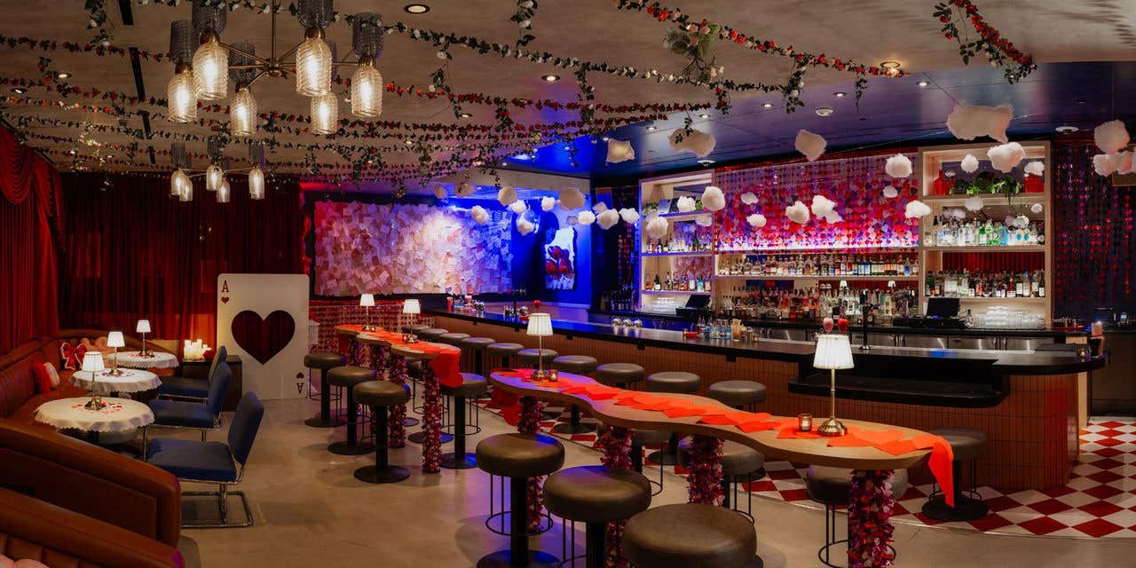 Valentine’s‑themed speakeasy bar decorated with red and pink garlands, heart accents, and festive lighting.
