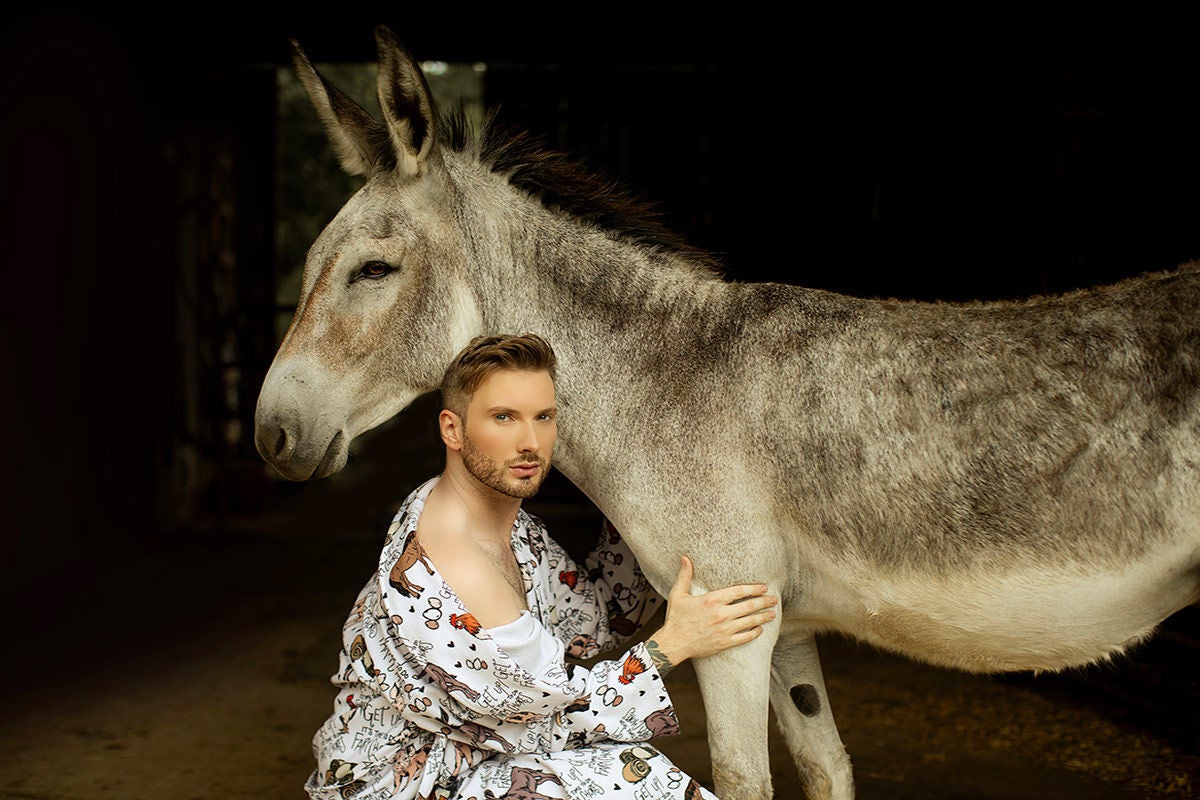 Matt Mathews crouching next to a donkey.