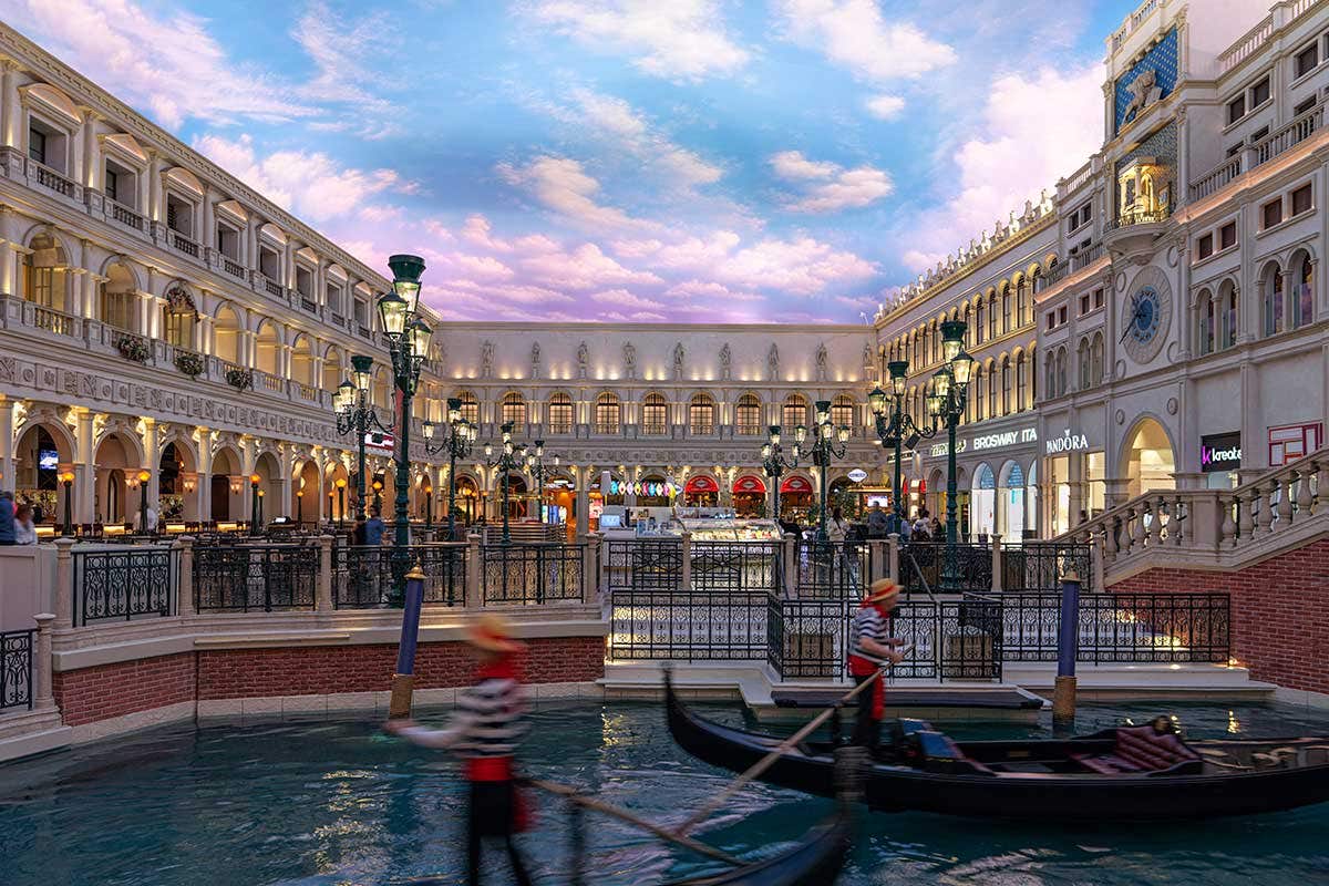 St. Mark’s Square in the Grand Canal Shoppes with gondoliers piloting gondolas in front.