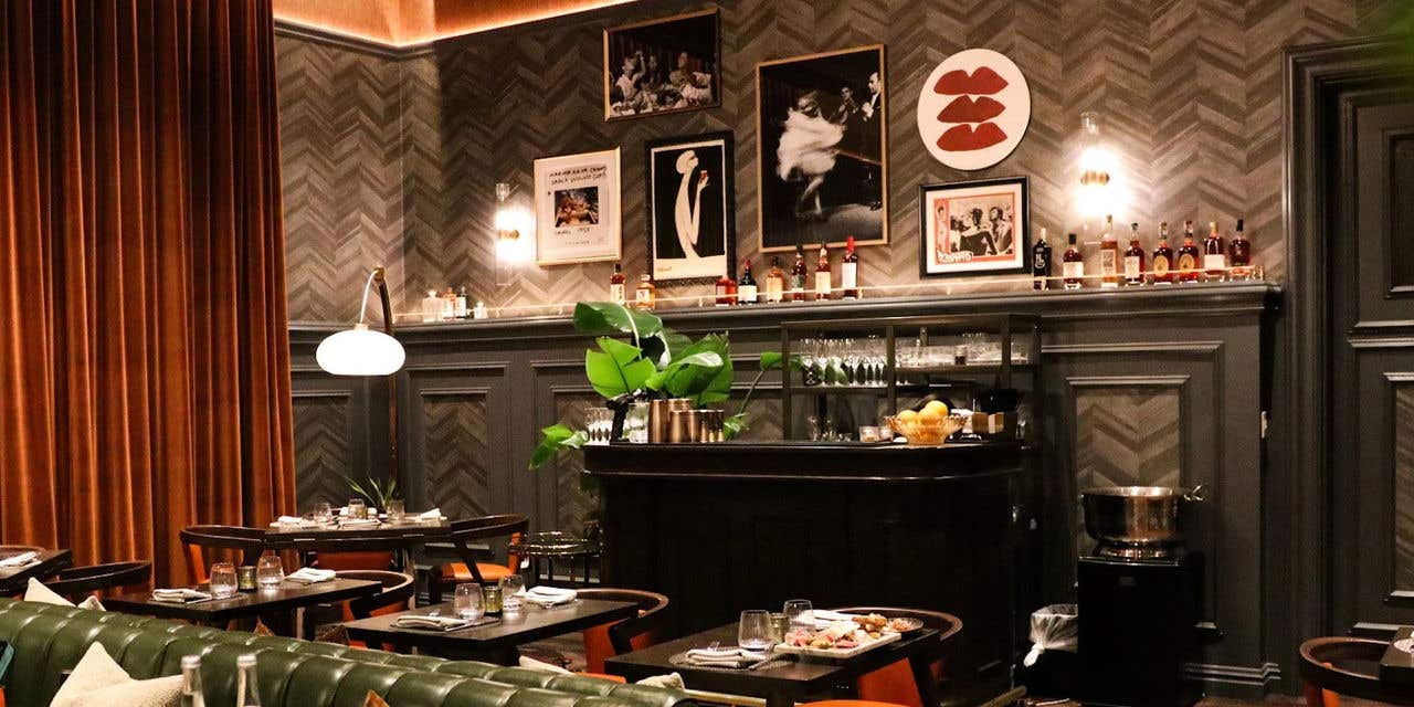 Elegant restaurant interior with dark wood paneling, plush booth seating, and warm lighting.