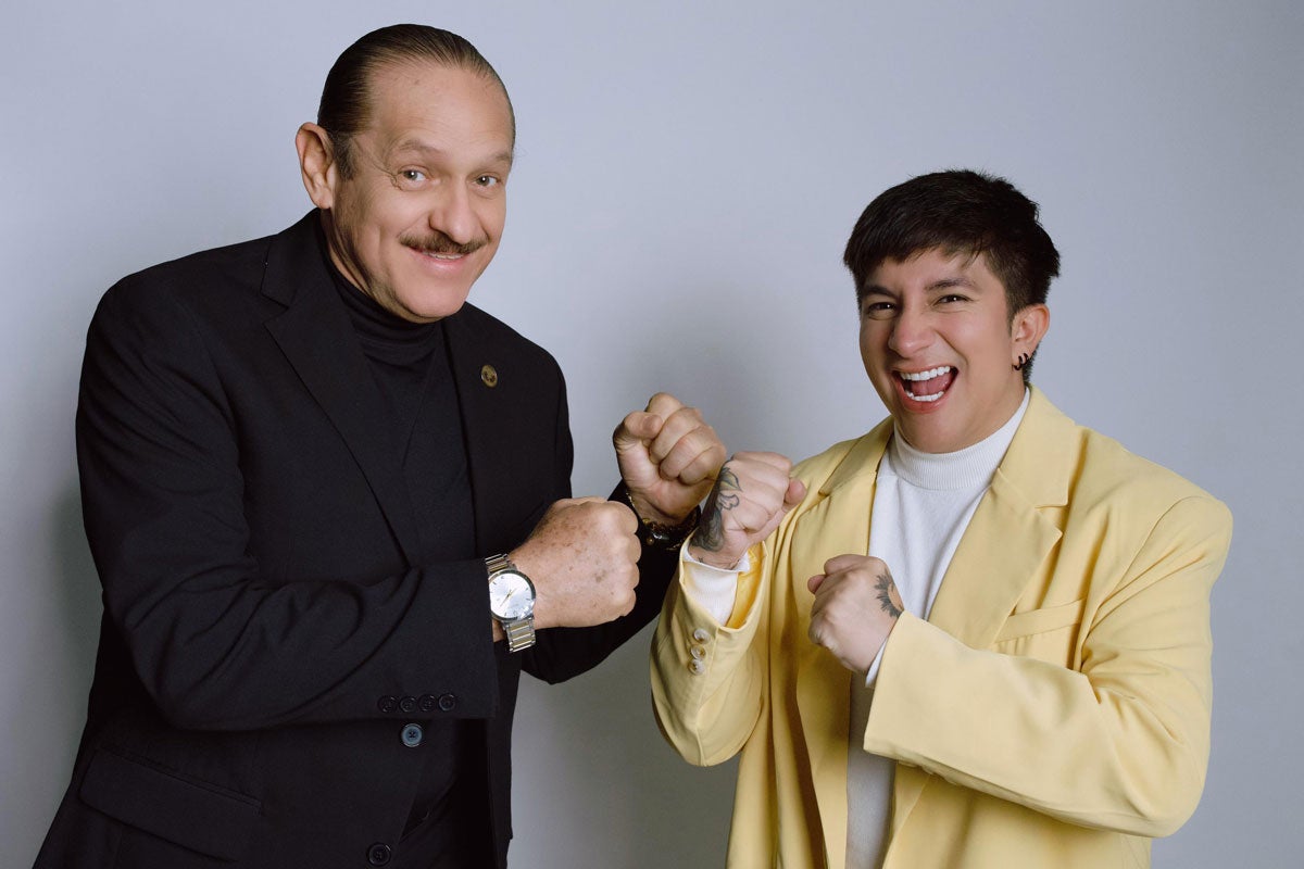 Teo González & Mario Aguilar smiling, posing with fists up; one in a black suit, the other in a yellow blazer.
