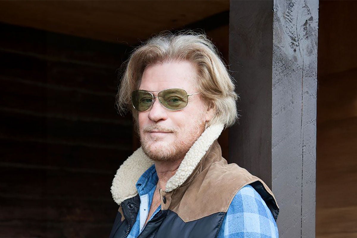 Daryl Hall wearing a plaid shirt and shearling jacket with sunglasses.