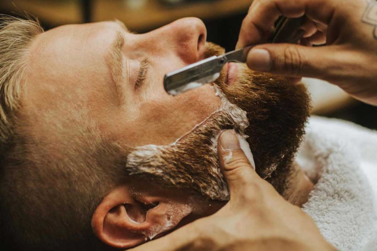 A barber trims a man’s beard.