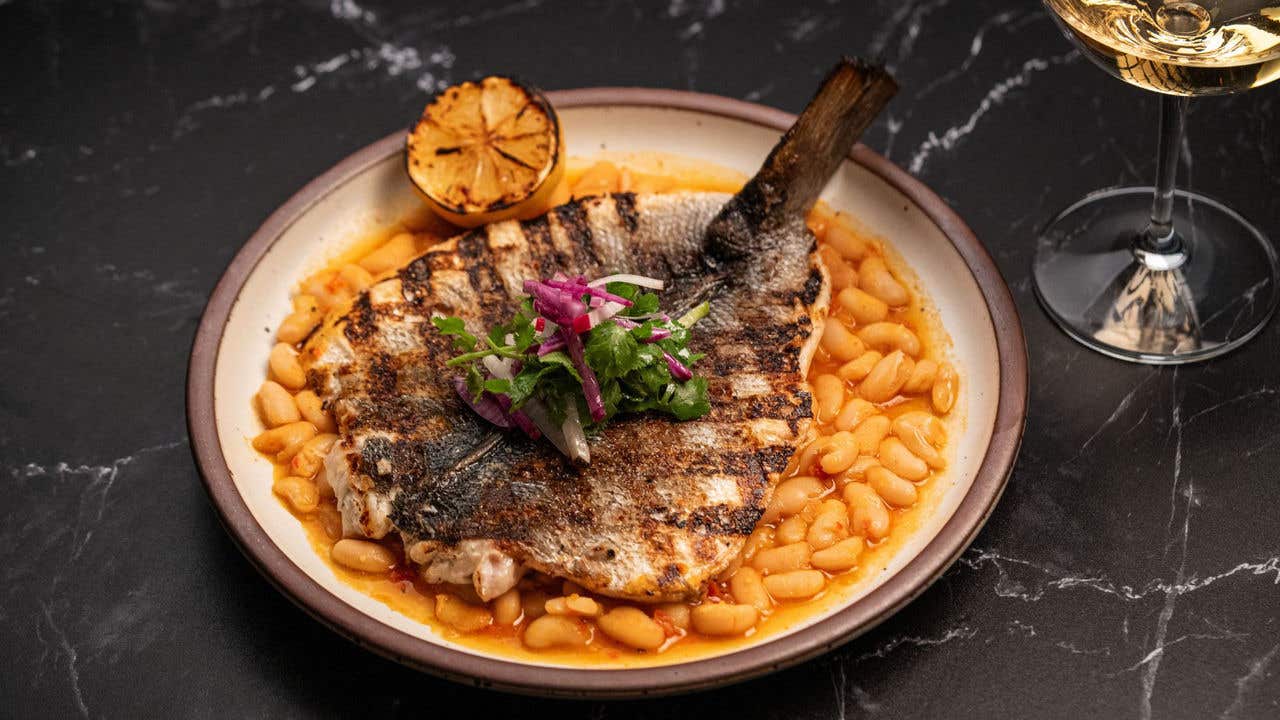 Grilled branzino served over white beans with lemon.