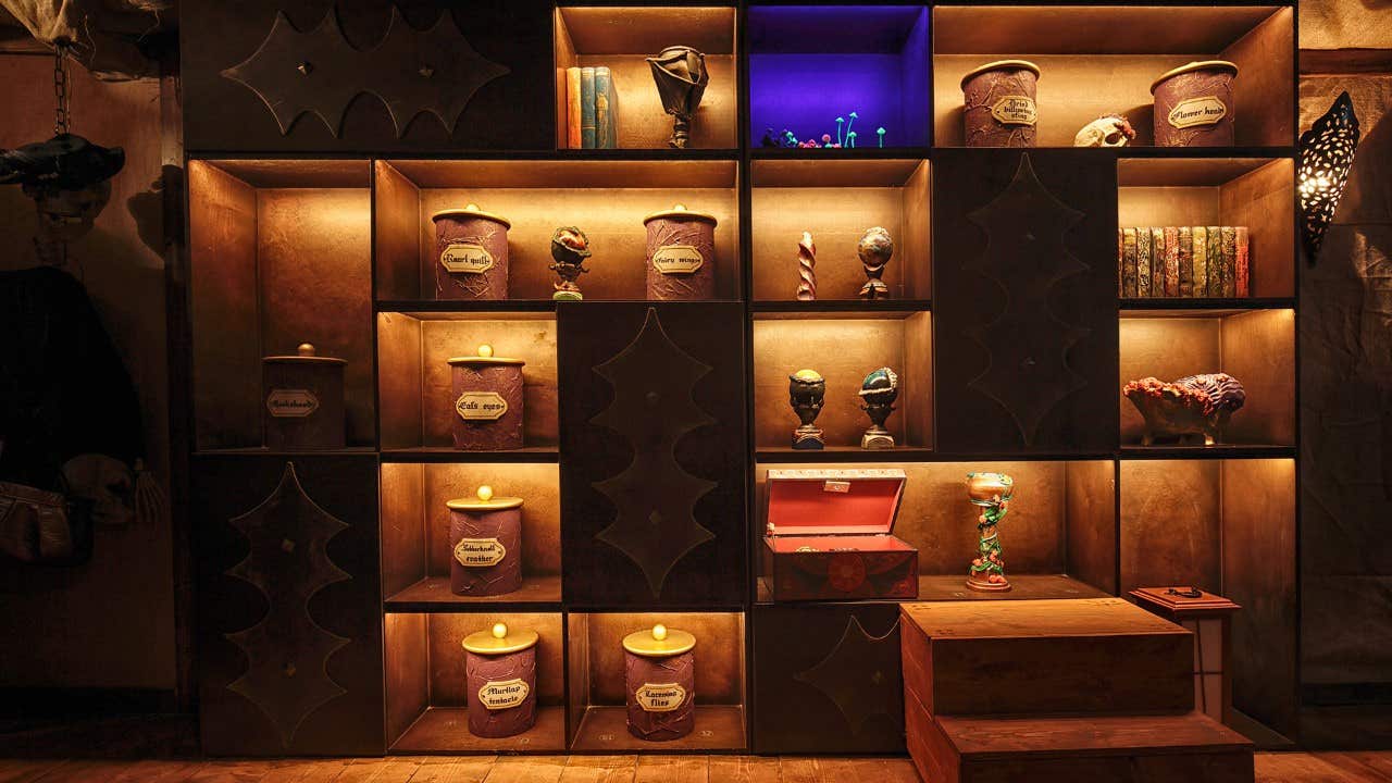 A dimly lit shelf with jars, books, sculptures, and a glowing purple compartment, creating a mysterious atmosphere.