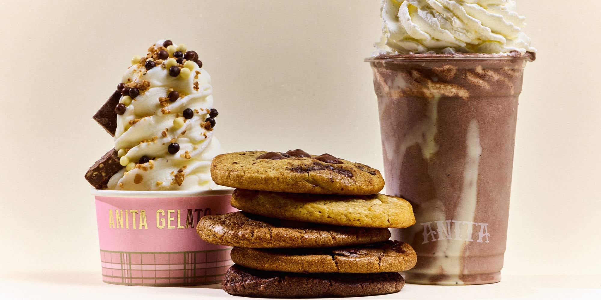 Gelato and chocolate shake topped with whipped cream, alongside a stack of cookies on a neutral background.