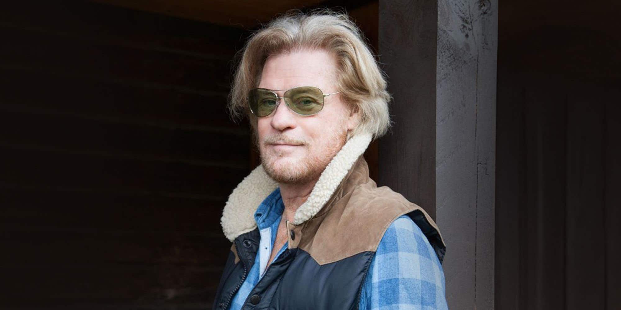 Daryl Hall wearing a plaid shirt and shearling jacket with sunglasses.