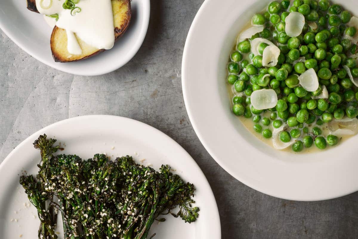 Plates of seasonal vegetables, including sweet peas, broccolini, and grilled bread.