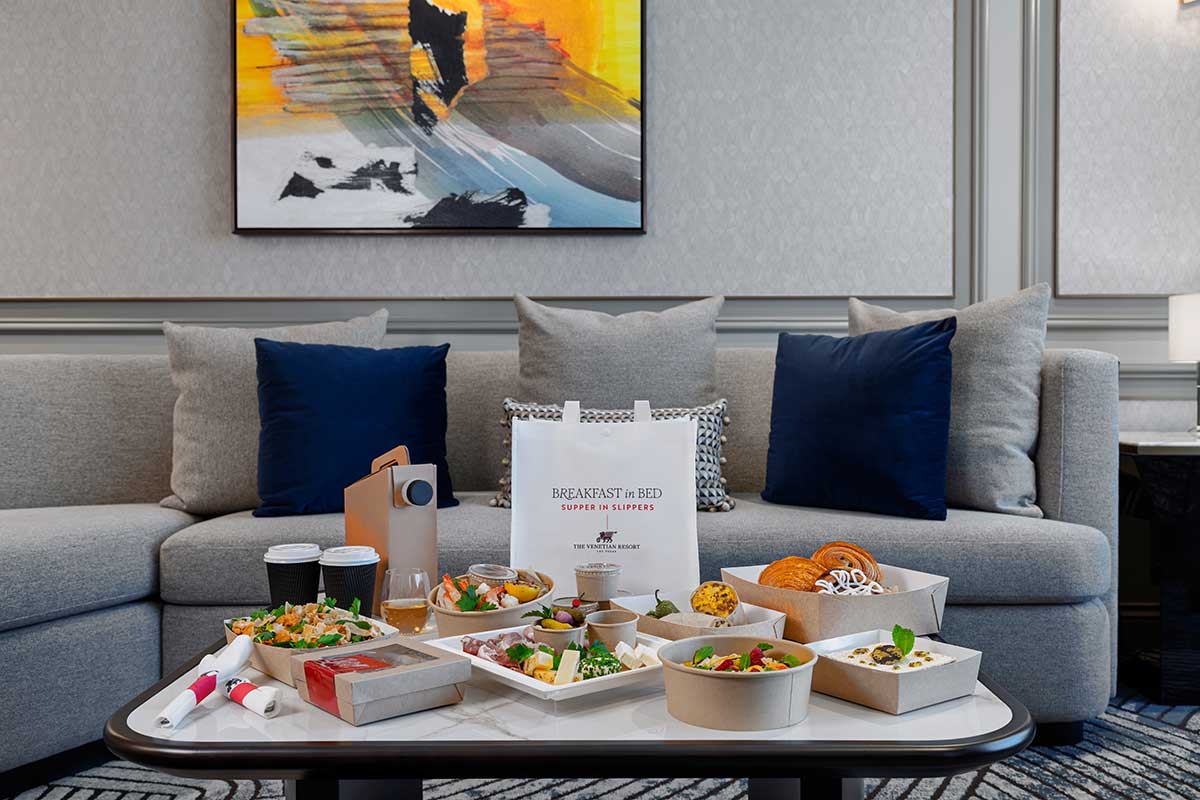 a spread of food on a coffee table in front of a gray couch in a hotel lobby
