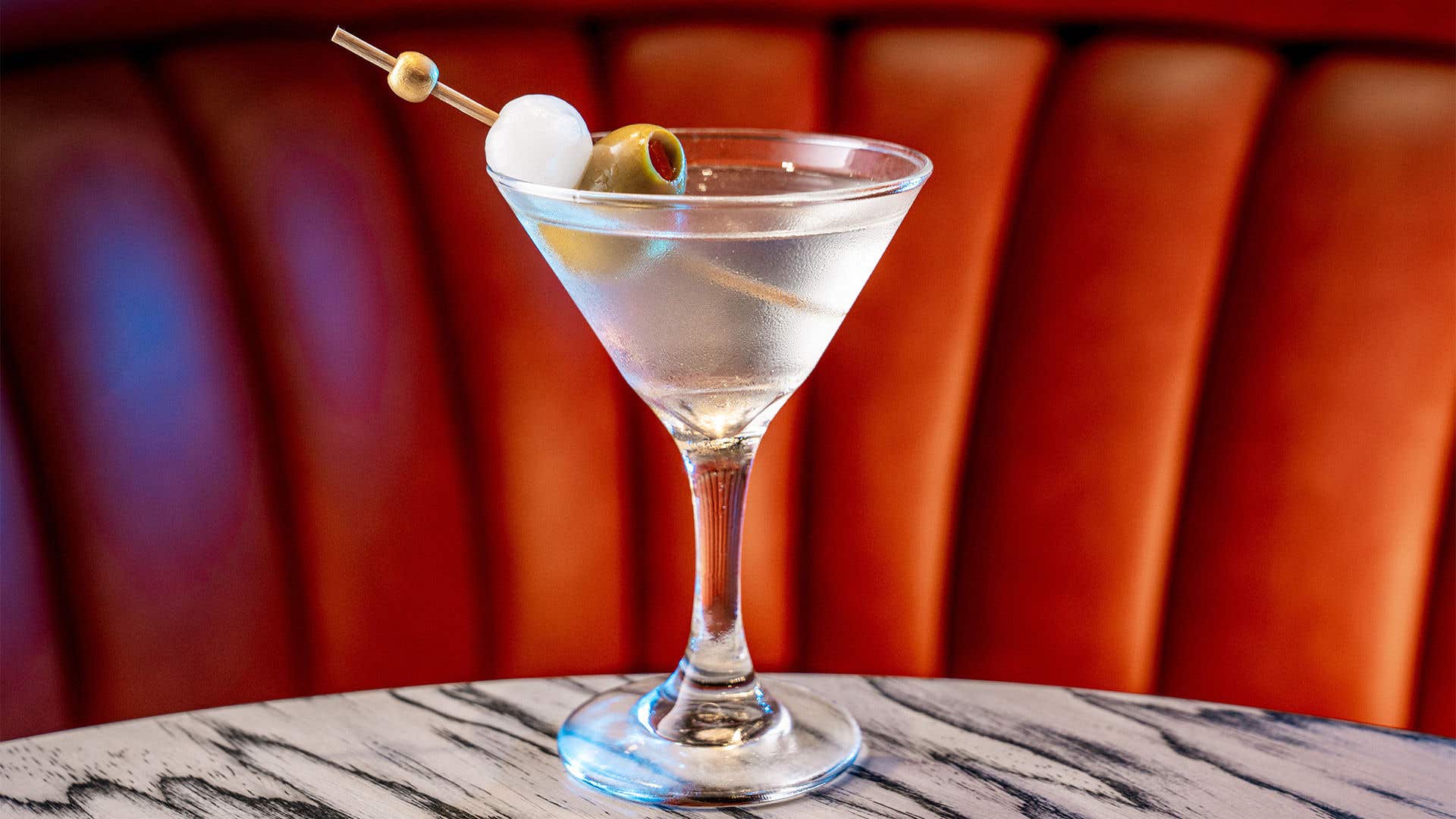 Clear liquor in a martini glass garnished with an onion and an olive. 