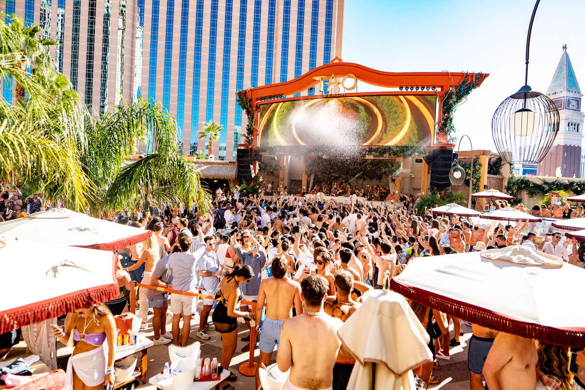 A large group of people partying and dancing to the music near the dj podium at TAO Beach.